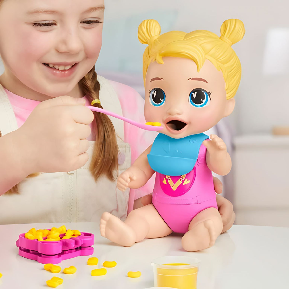 Criança a alimentar a Baby Alive Jantar Criativo com comida de brincar amarela e talher rosa