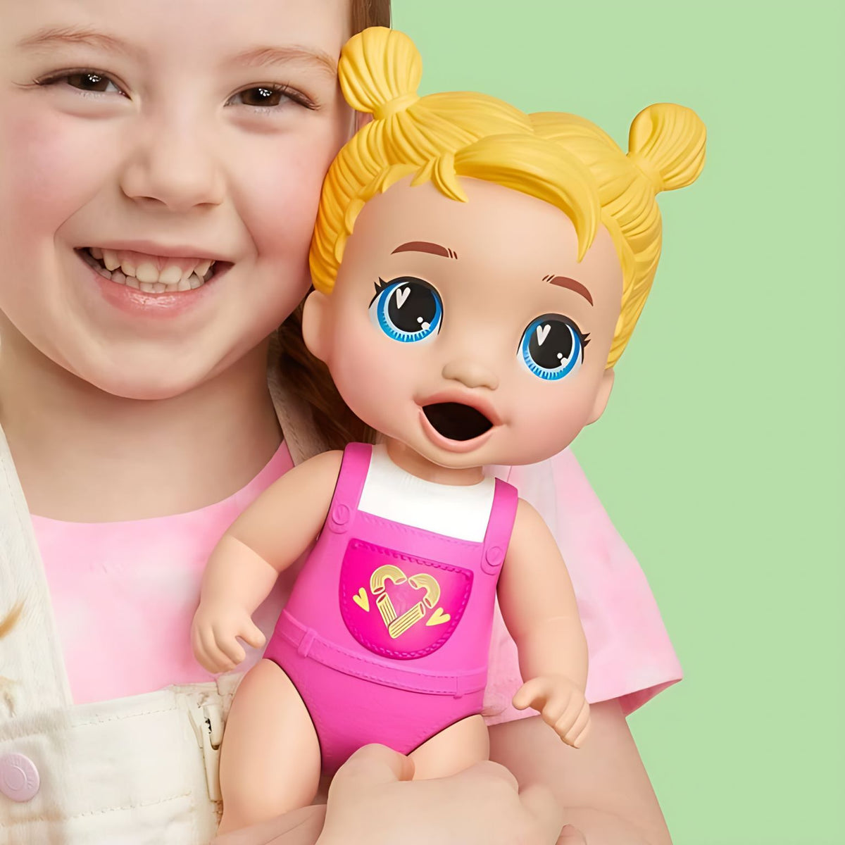 Criança com a boneca Harper Hugs, de cabelo loiro em dois coques e roupa rosa moldada