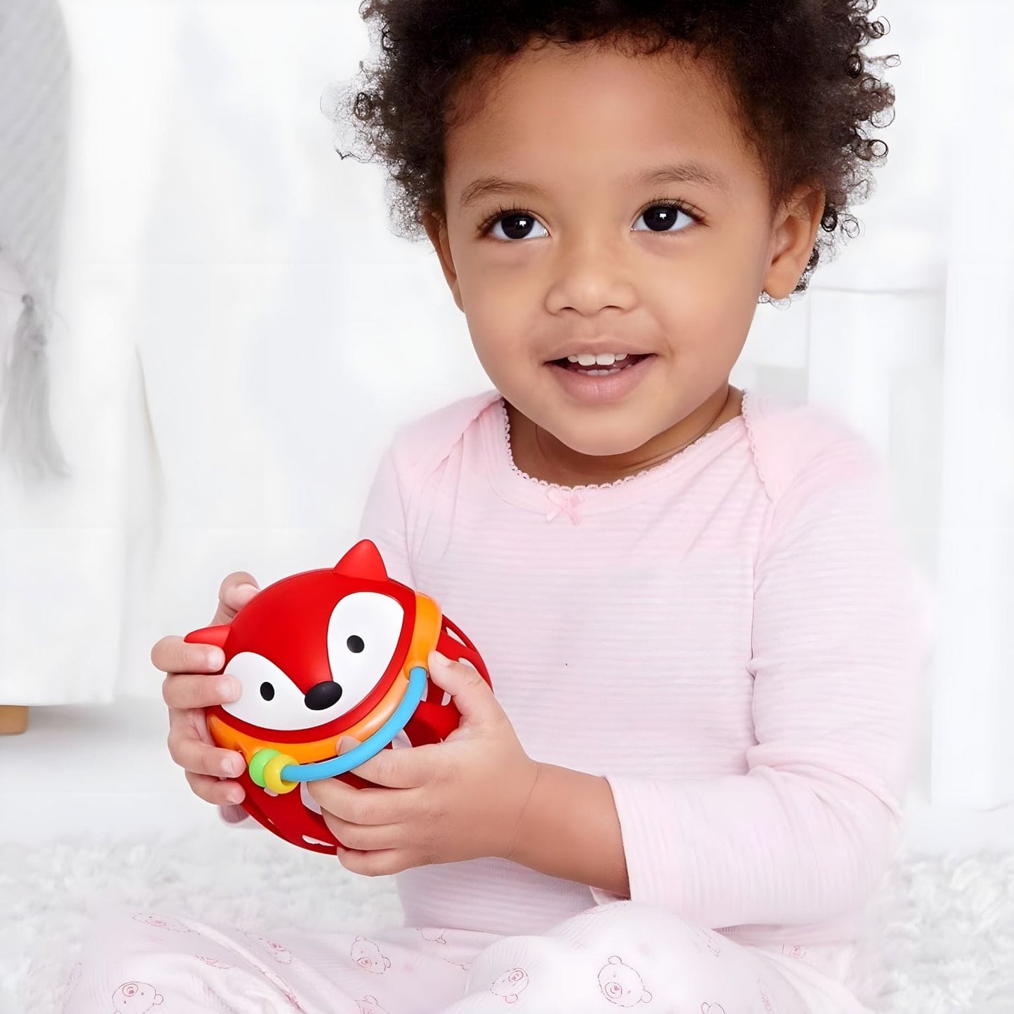 Bola Chocalho Raposa vermelha da Skip Hop nas mãos de bebés em momento de descoberta