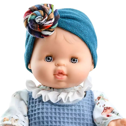 Muñeca Blanca de Paola Reina con ropa azul, cuello blanco y turbante azul con flor colorida