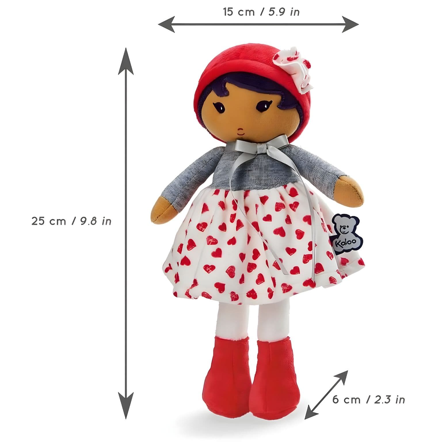 Boneca de Pano Jade da Kaloo com vestido branco de corações vermelhos, camisola cinzenta e gorro vermelho