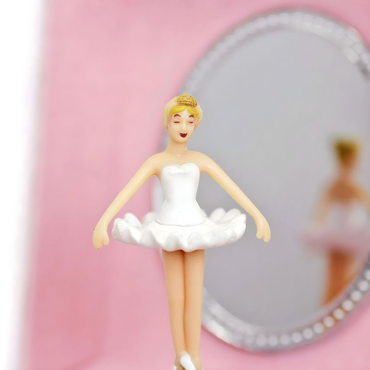 Pormenor da bailarina de vestido branco diante do espelho da caixa musical rosa