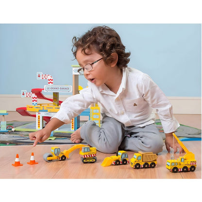 Niño jugando con vehículos de construcción de madera Le Toy Van, incluyendo camión, grúa, excavadora, pala y conos.