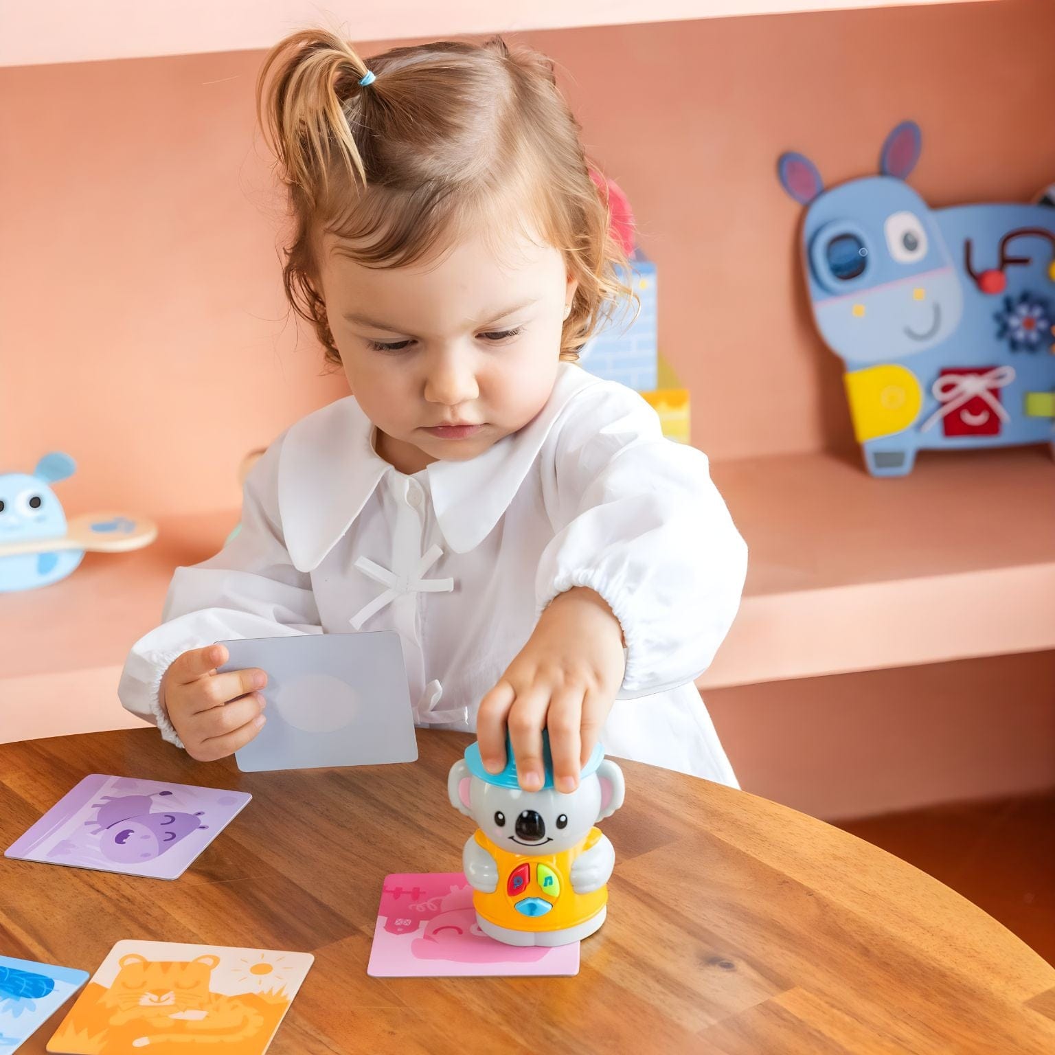 Criança a brincar com o Jogo Eu Aprendo: Aprendo com Coco da Diset com cartas ilustradas e boneco interativo
