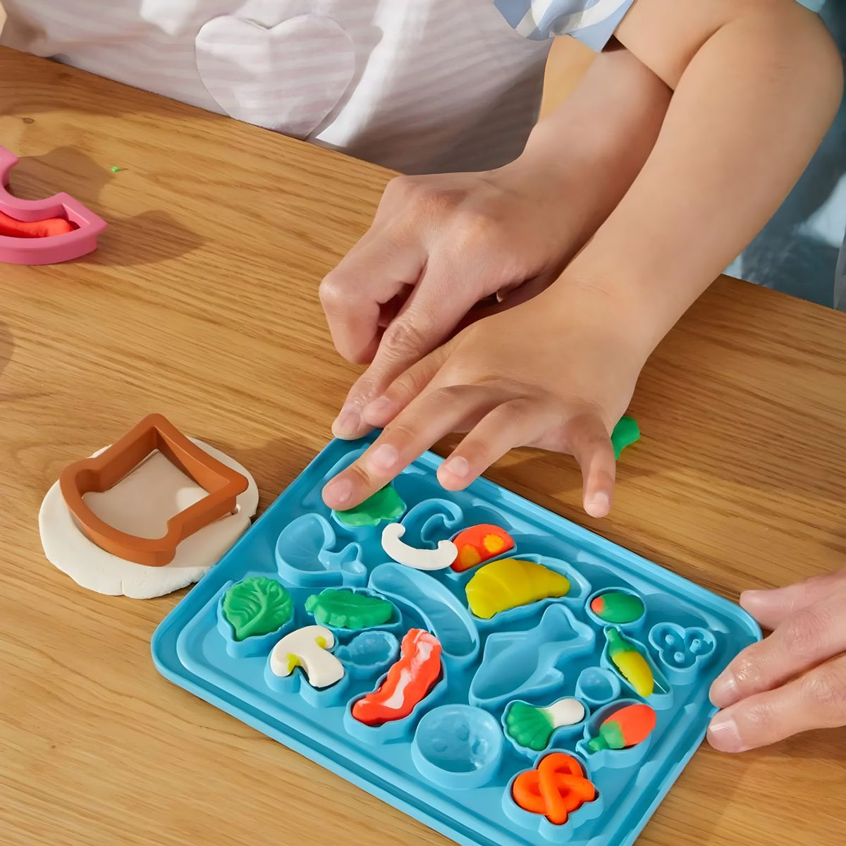 Criança a preencher os moldes da tampa azul com massa Play-Doh colorida
