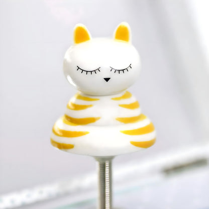 Detalle de la figura del Gato Bailarín, blanca con rayas amarillas y ojos cerrados